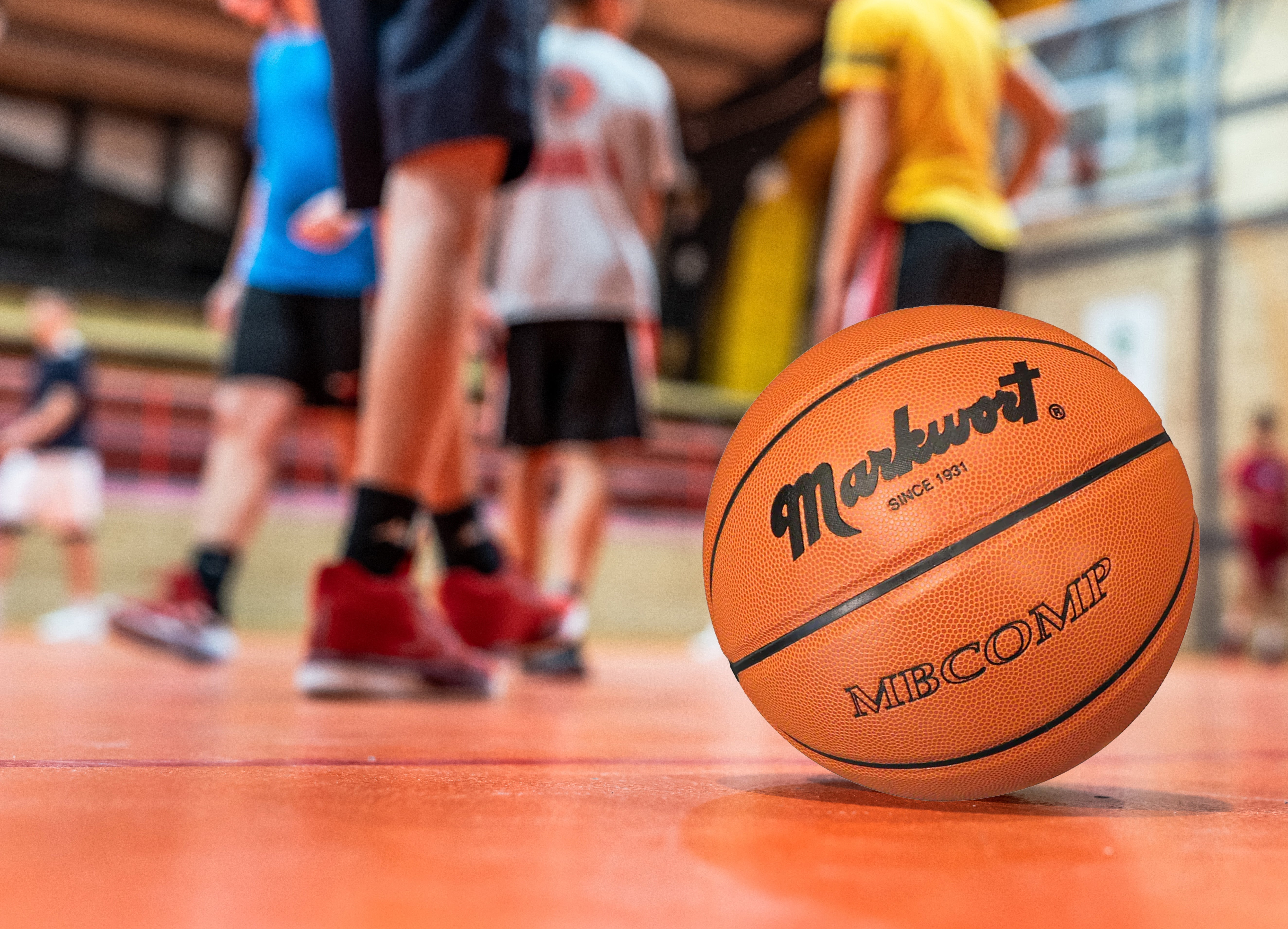 Basketball with 'Markwort' branding on a basketball court with players in the background